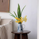 Blue and white porcelain vase with pomegranate design holding fresh flowers in living room décor.